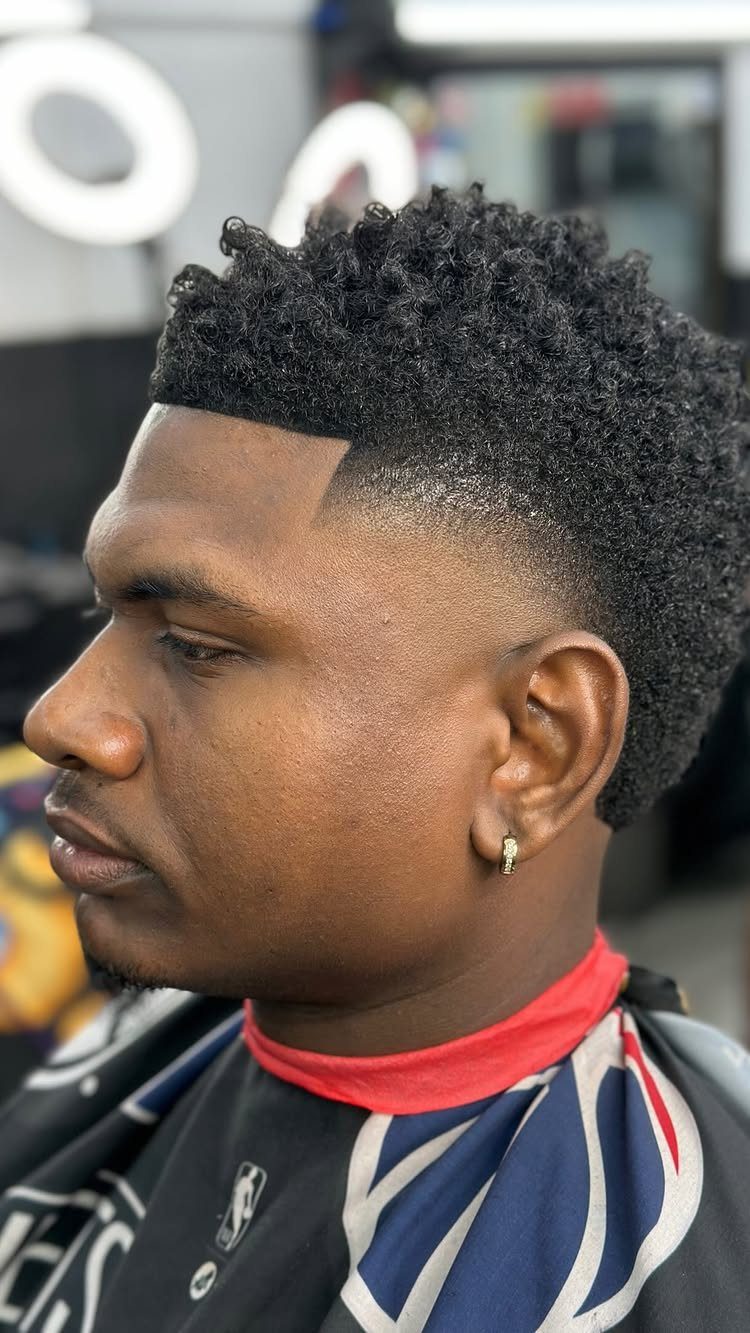Man with a burst fade haircut and curly hair on top in a barbershop