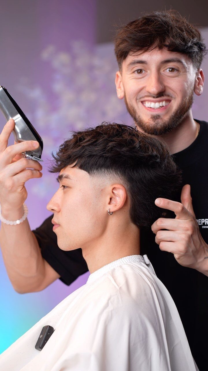 Barber cutting a burst taper fade on a young man with textured hair.