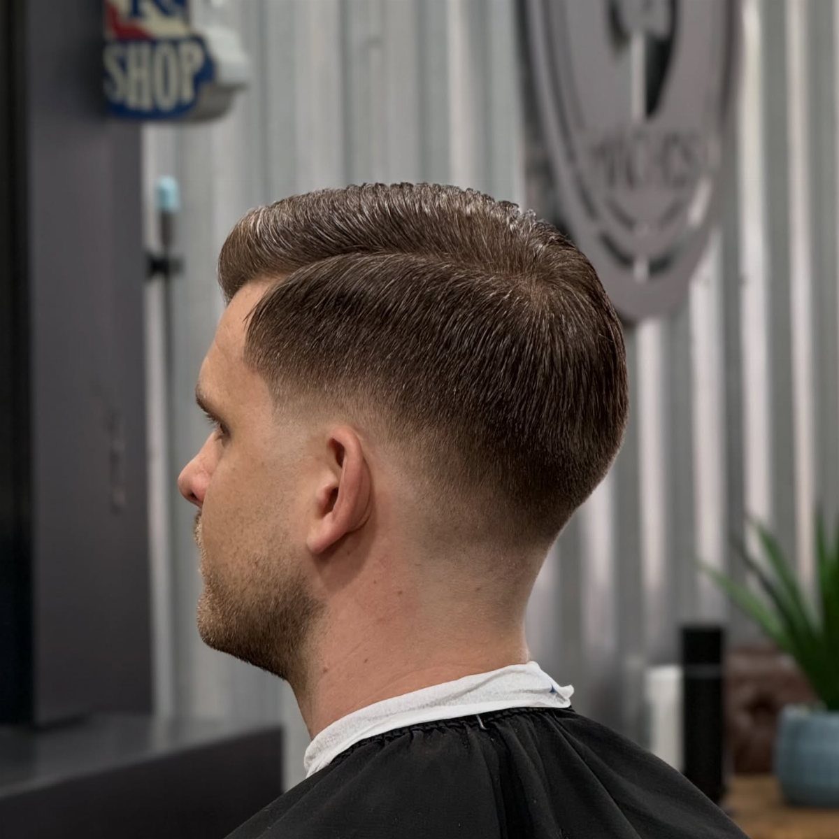 Man with a comb over hairstyle and low skin fade in a barbershop