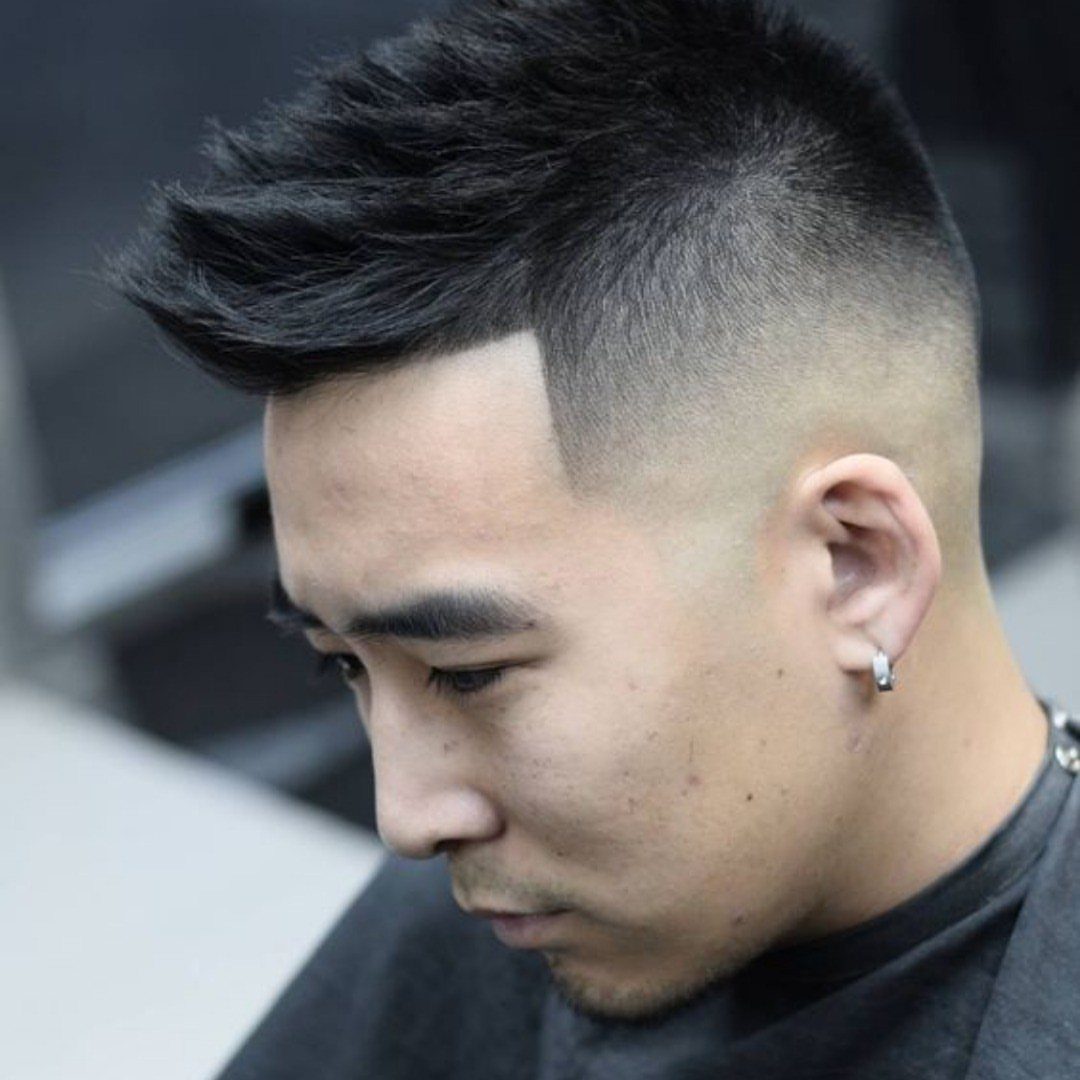 Man with a faux hawk haircut and high skin fade in profile view.