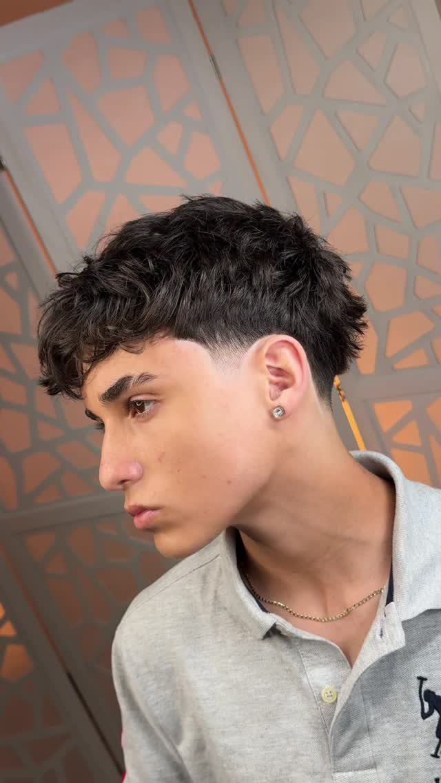 Young man with a low fade haircut and textured fringe over his forehead.