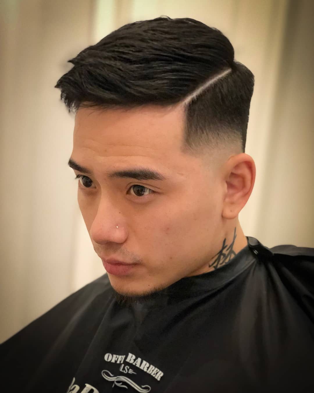 Man with a low burst fade and a combed over side part hairstyle.