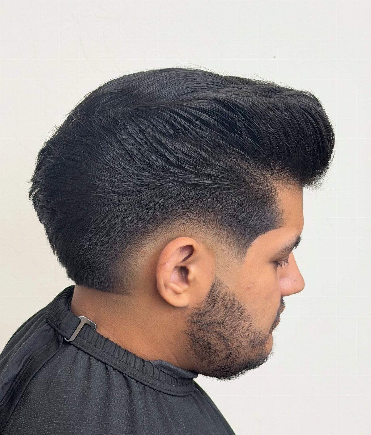 Man with a voluminous pompadour hairstyle and a low skin fade and beard.
