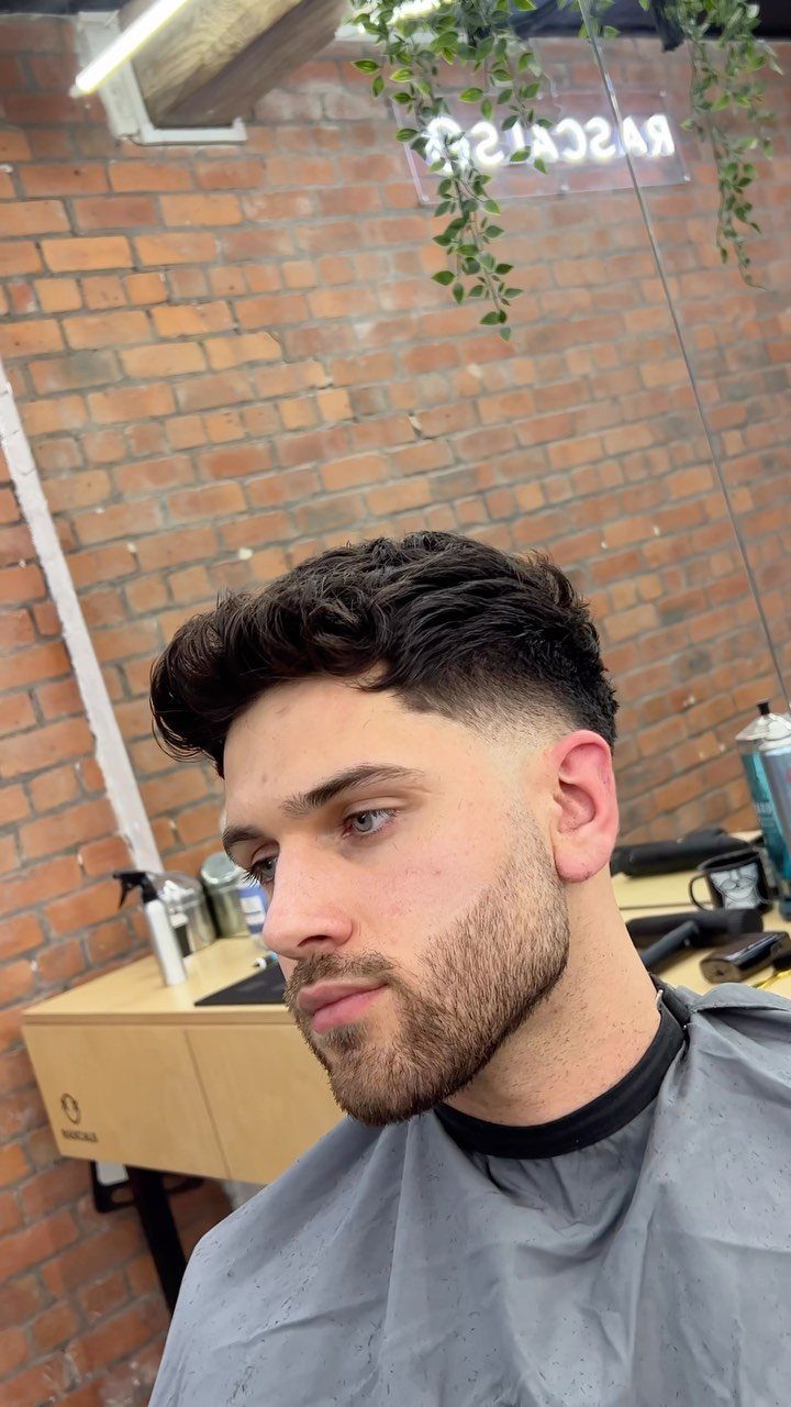 Man with a short quiff and low fade haircut in a barbershop setting.