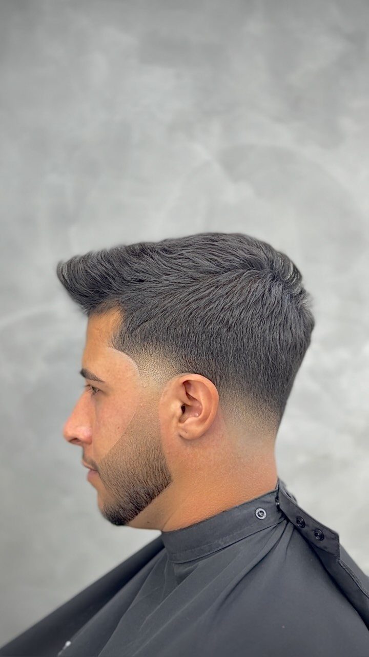 Man with a low skin fade and straight hair swept back on top.