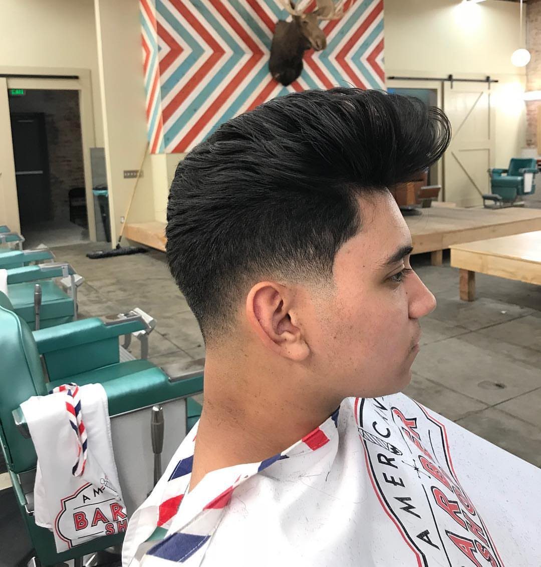 Man with a pompadour hairstyle and low fade in a barbershop setting.