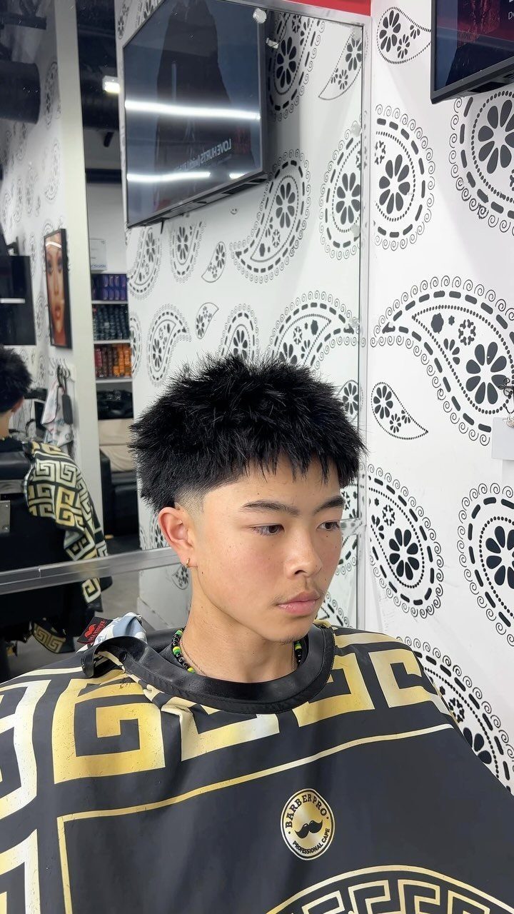 Young man with spiky textured hair and a low fade in a barbershop.
