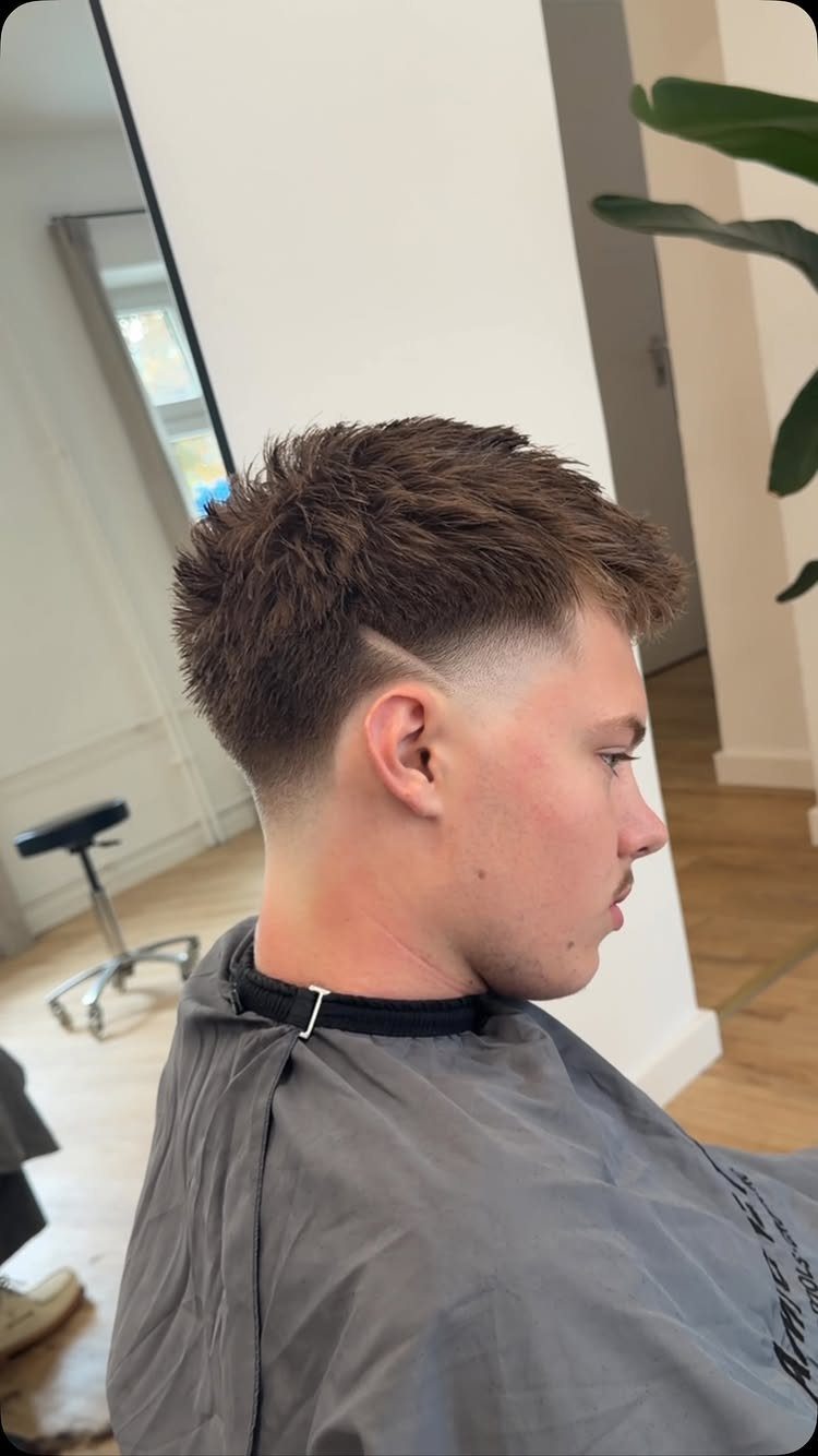 Young man with a textured brown haircut and a clean low taper fade.