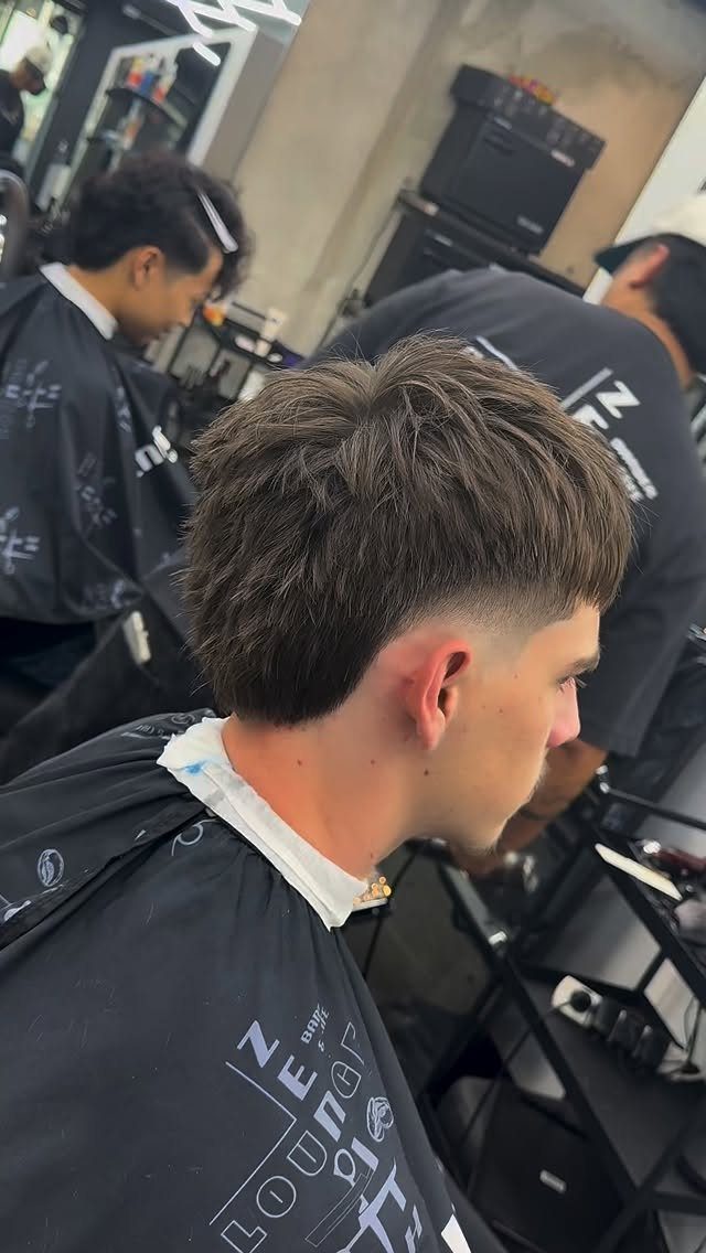 Man with a textured low burst fade haircut in a professional barbershop setting.