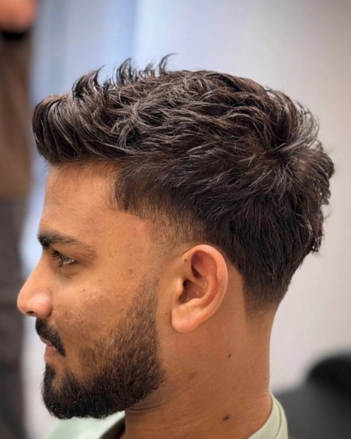 Man with textured wavy hair on top and a low skin fade haircut.