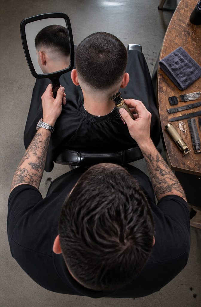 Barber marking a curved fade guideline and checking it behind the chair