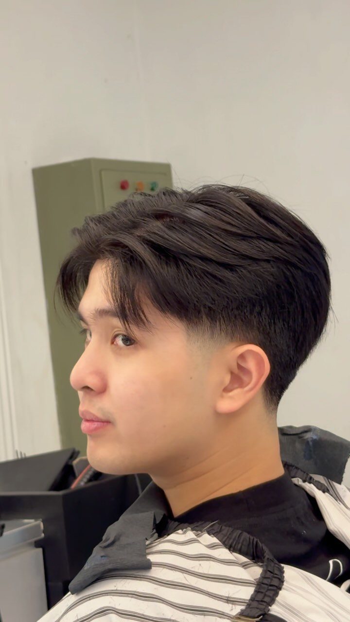Young man with a voluminous blowout taper haircut and low faded sides.