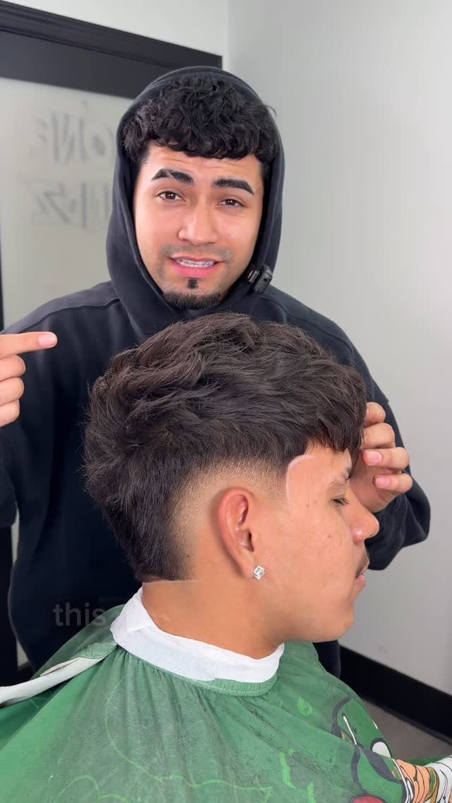 Man with a burst fade haircut and wavy top in a barber shop.