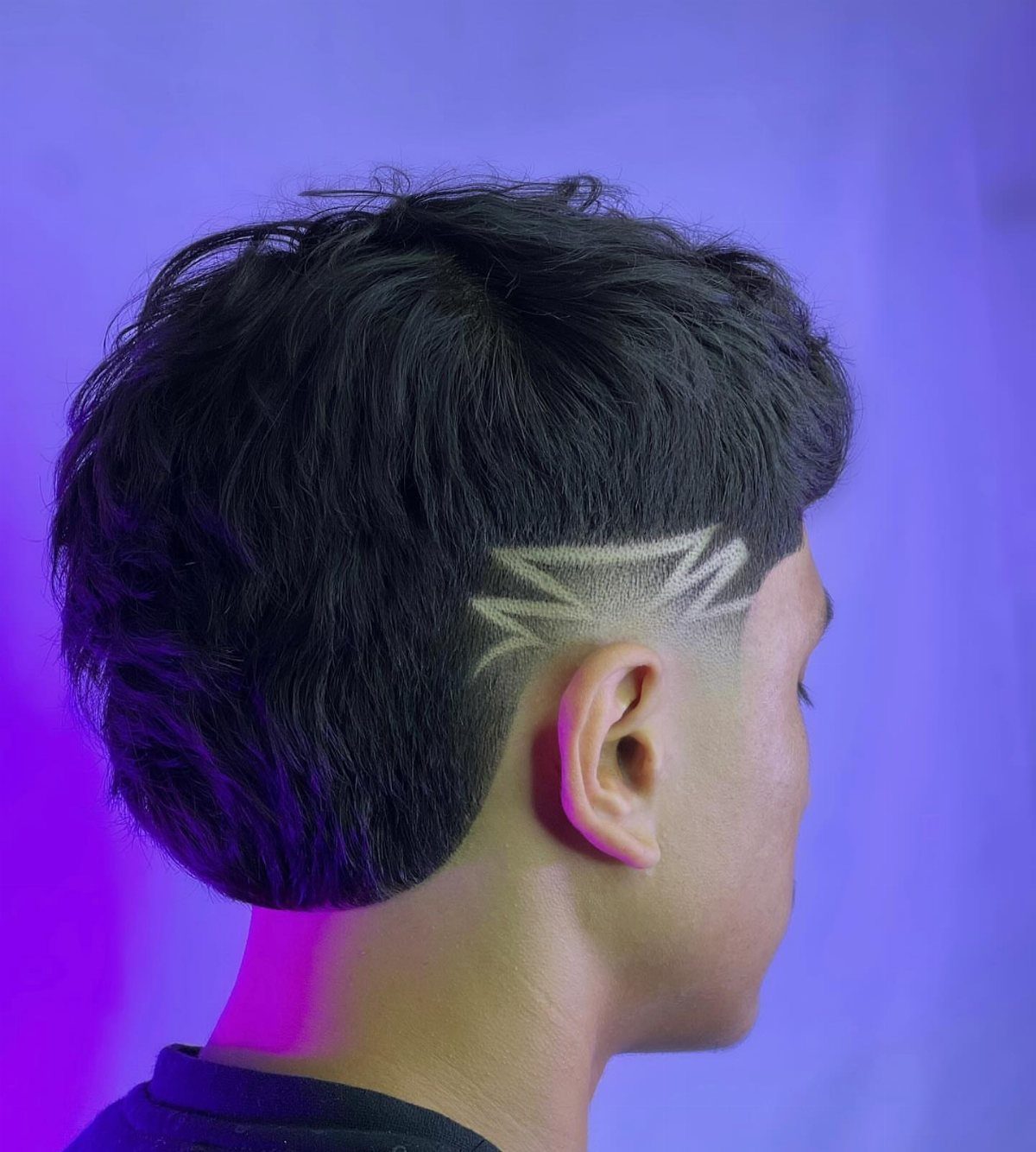 Man with black hair featuring a carved geometric design in a burst fade.