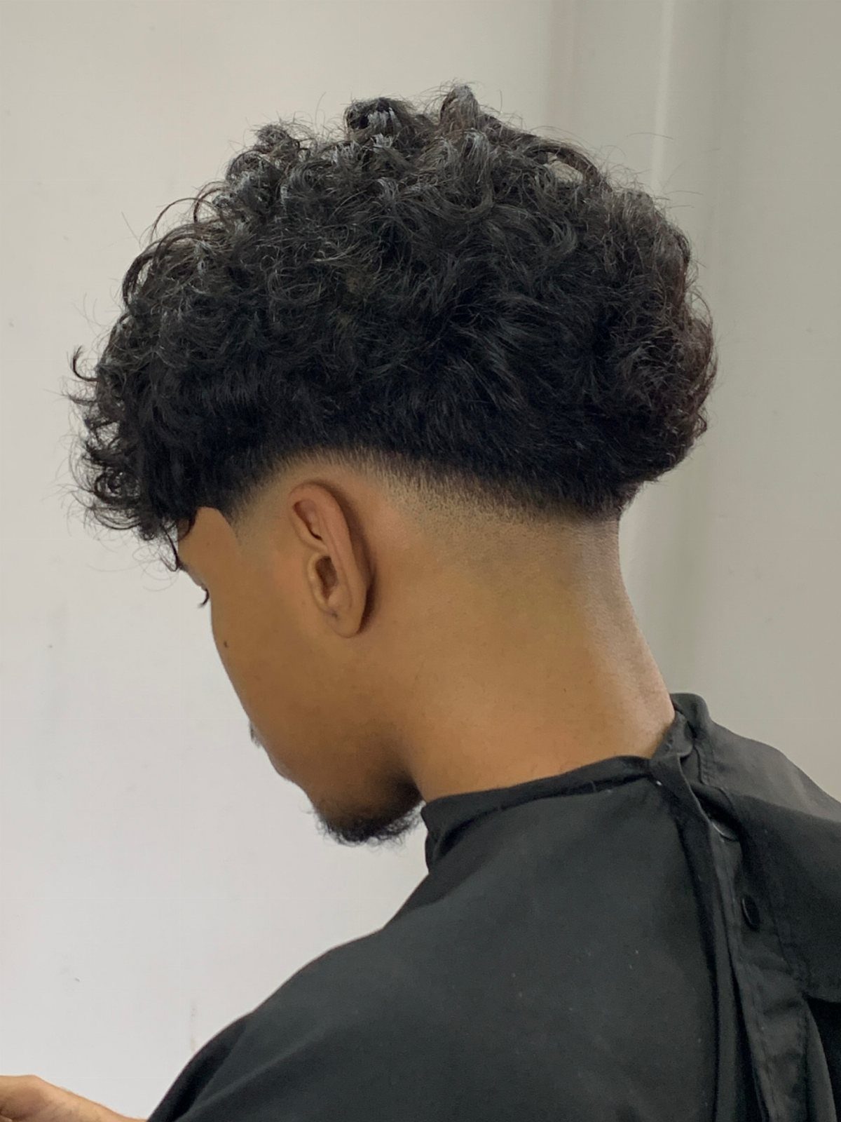 Man with curly hair on top and a low fade haircut side profile
