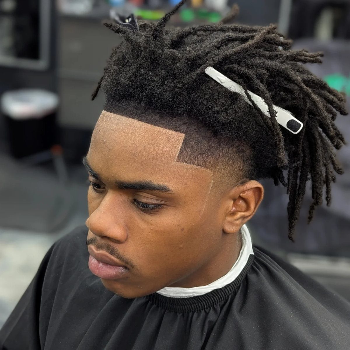 Man with dreadlocks featuring a sharp line up and low fade haircut.