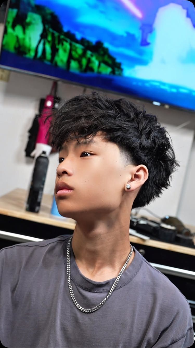 Young man with curly hair on top and a low taper fade haircut