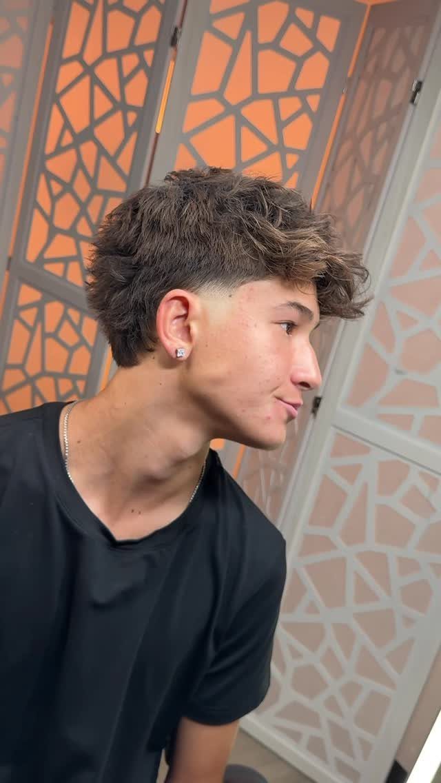 Young man with a low fade haircut and textured fringe falling forward.