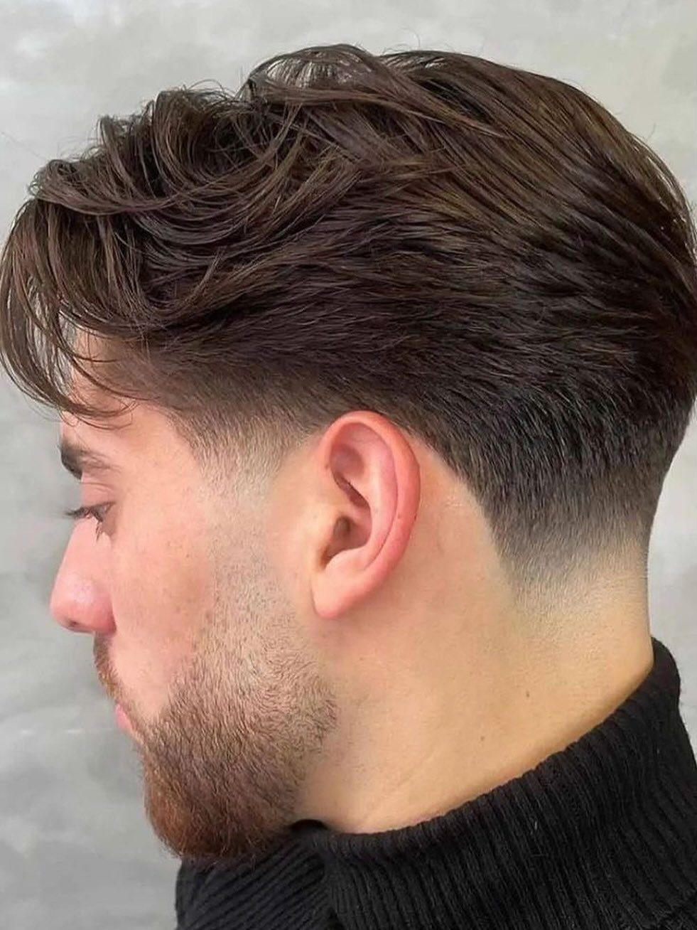Man with a low fade haircut and voluminous heavy layers on top.