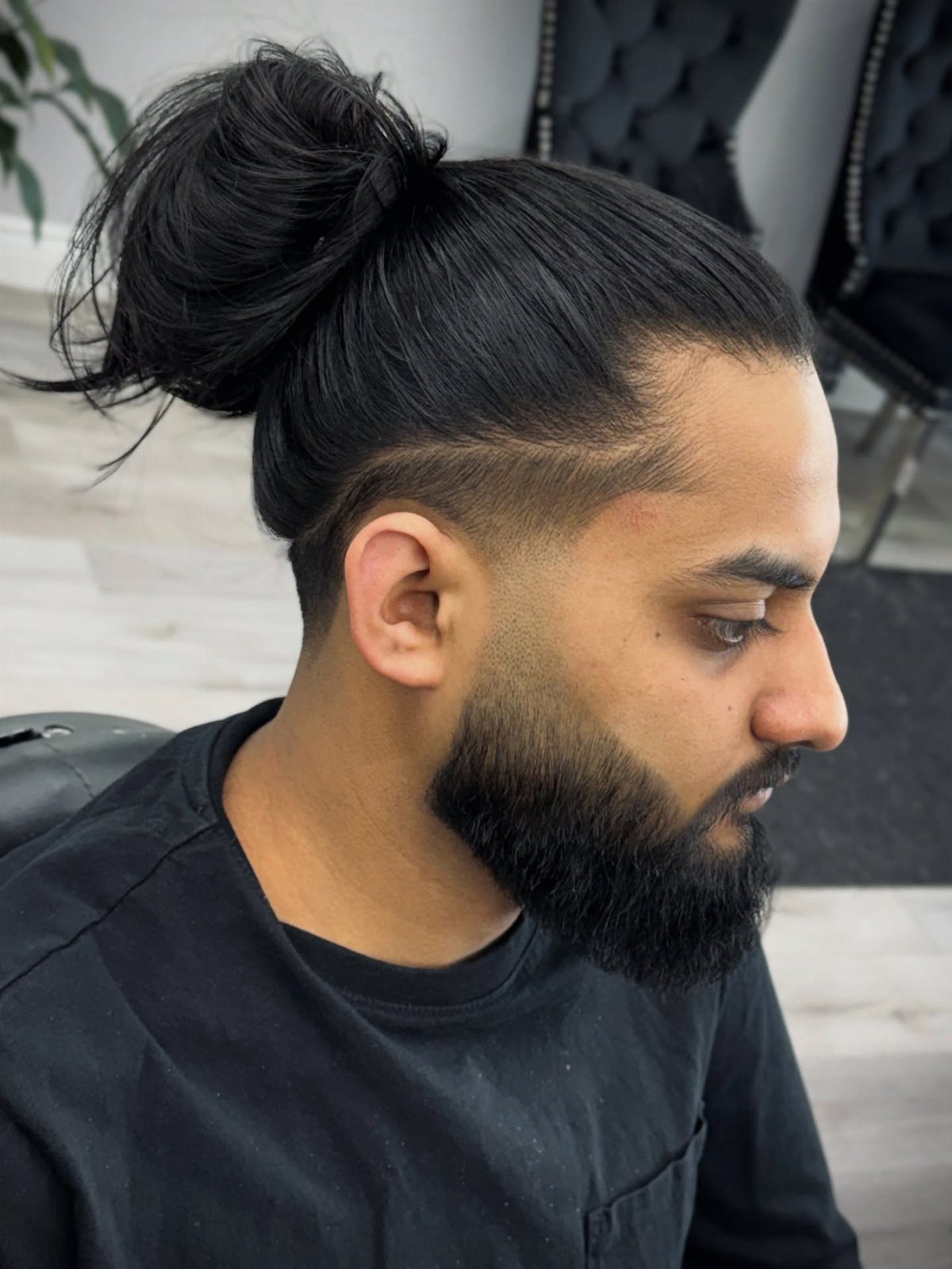 Man with a low fade haircut and long hair tied in a man bun.
