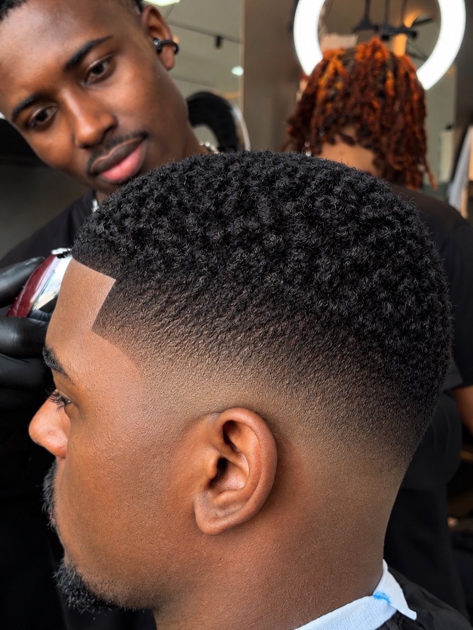 Man with a low fade haircut and natural curly texture on top.