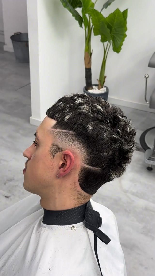 Man with a low fade haircut and silver highlights in a barber shop