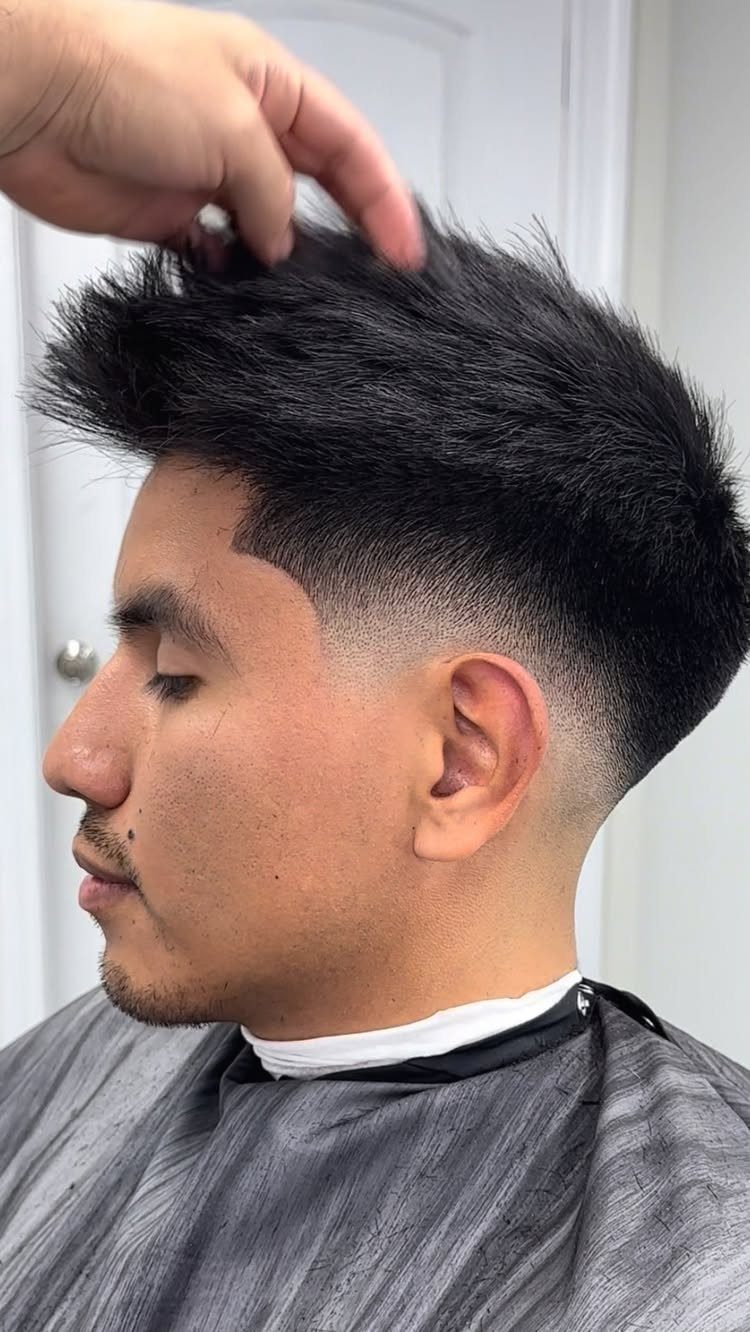 Man with thick black hair featuring a low skin fade and textured top.