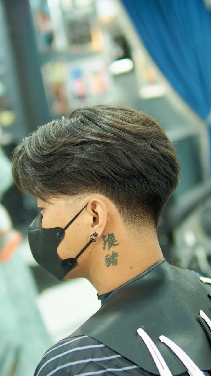 Man with a brown low taper fade haircut and a neck tattoo.
