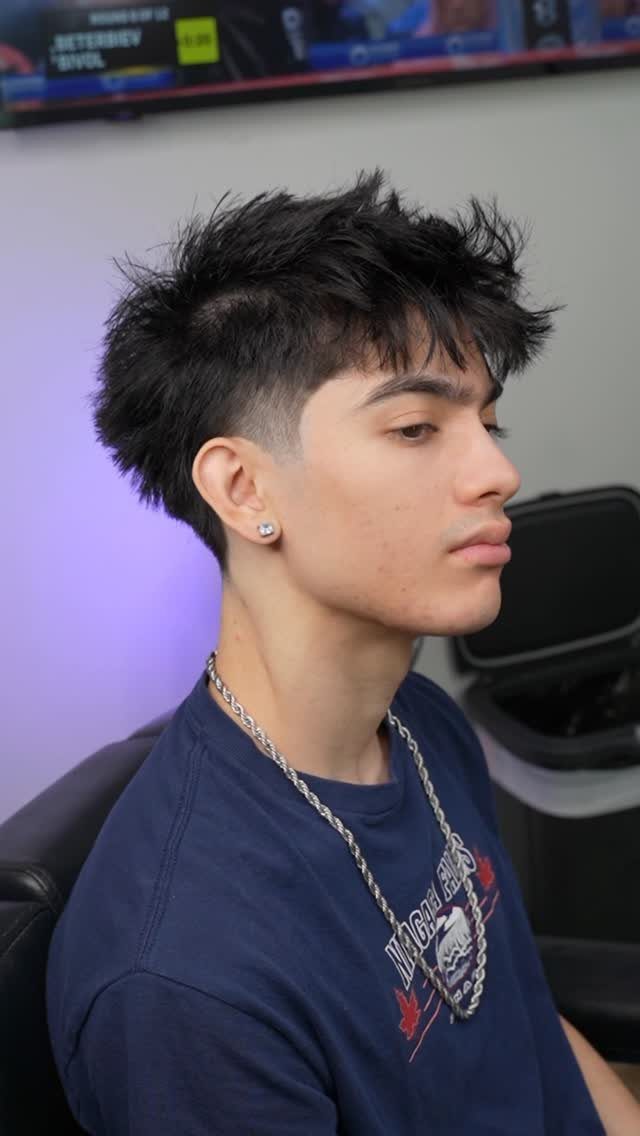 Young man with a messy fringe haircut and low fade in a barbershop.