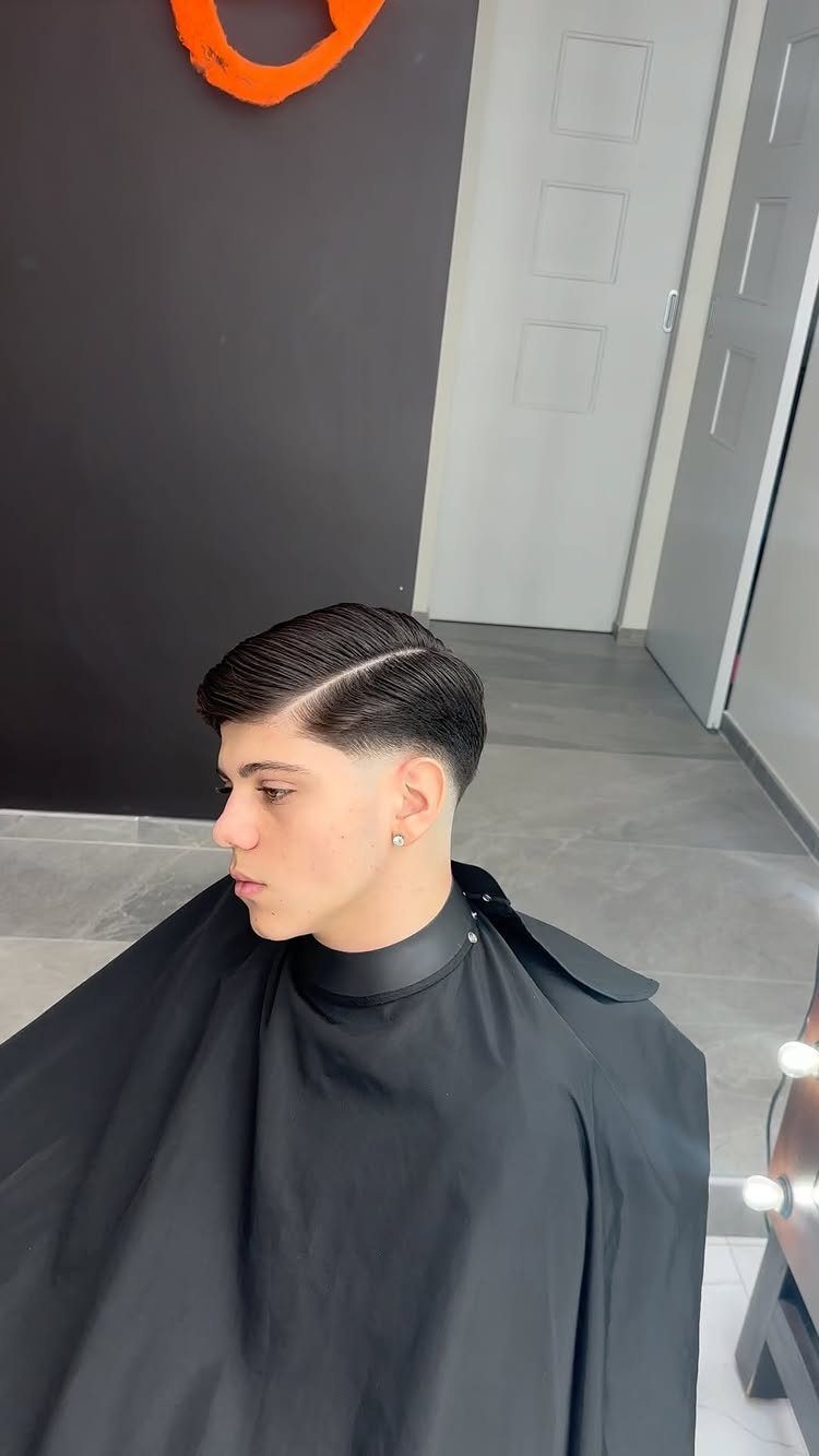 Young man with a polished side part haircut and low fade in a barbershop.