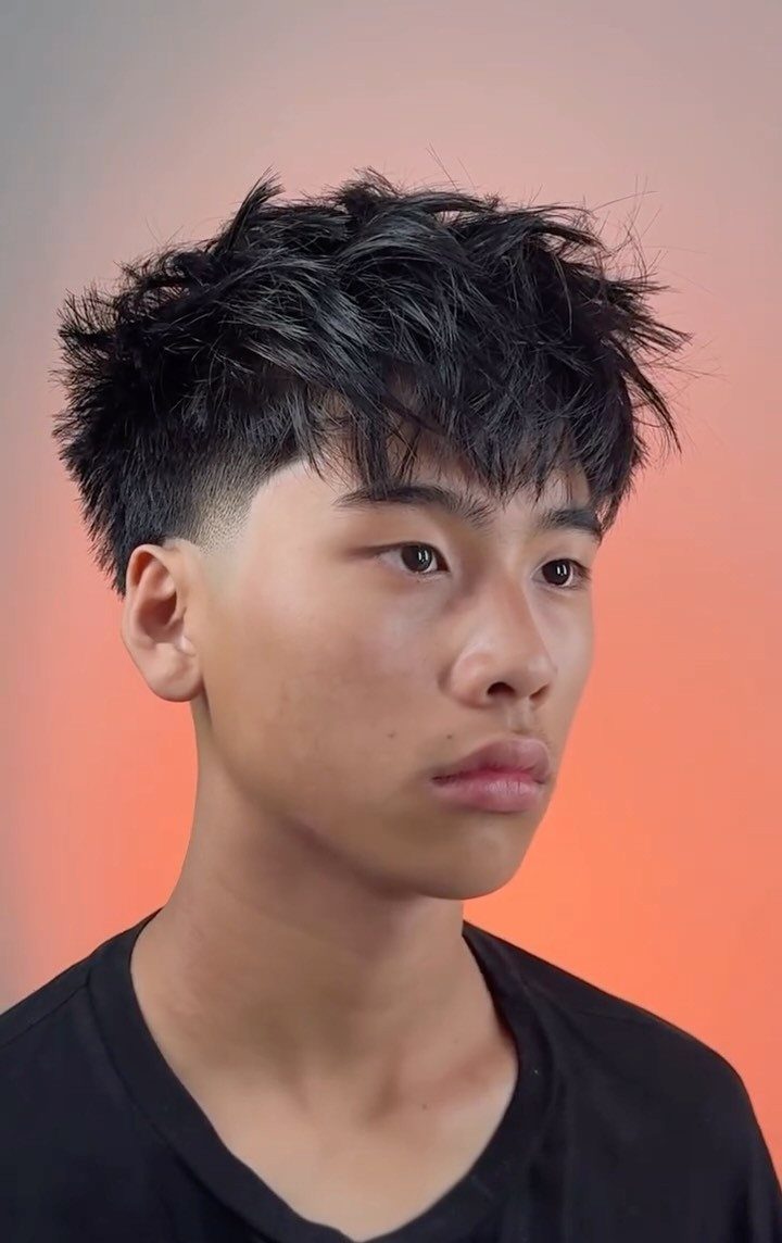 Young man with a textured crop haircut and low taper fade sides.
