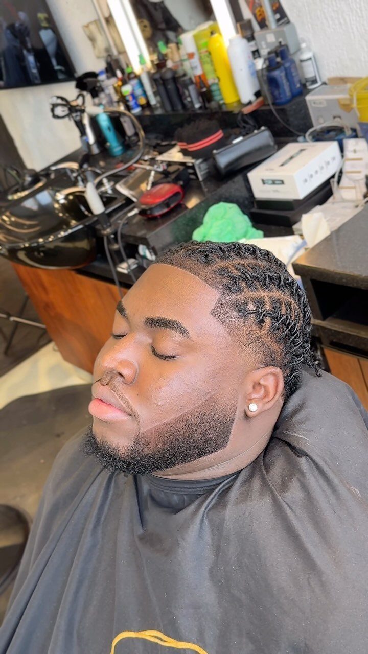 Man with a low taper fade and neat hair twists in a barbershop.