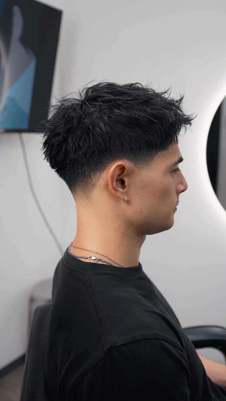 Man with a textured French crop haircut and low taper fade side profile