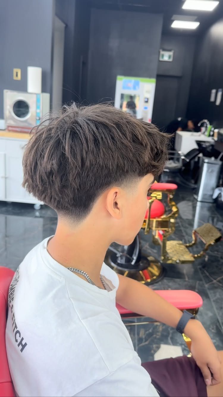 Young man with a low taper fade and messy textured hair on top.