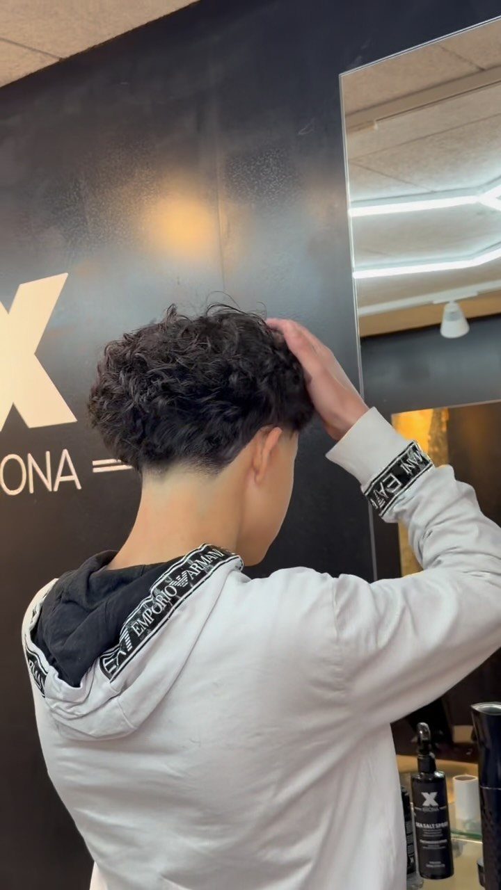 Man with a low temple taper fade and curly dark hair on top.