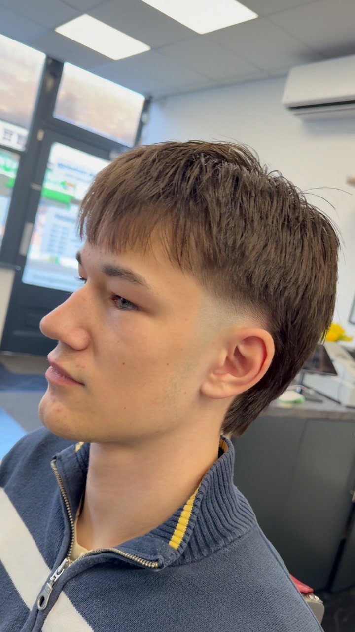 Young man with a brown mullet haircut featuring tapered sides and long back.