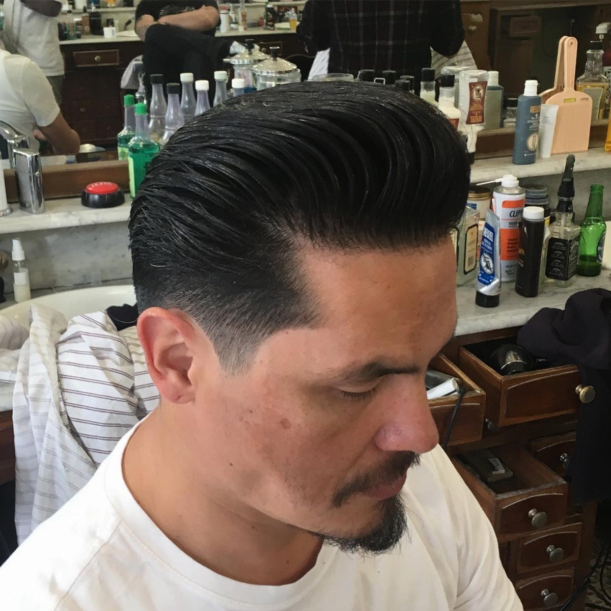 Man with a high-volume pompadour hairstyle in a barbershop setting.