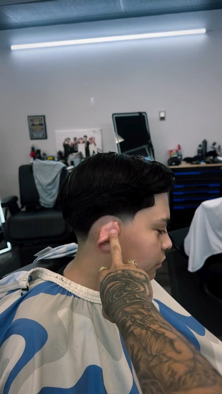 Man with a side part and low taper fade haircut in a barbershop.