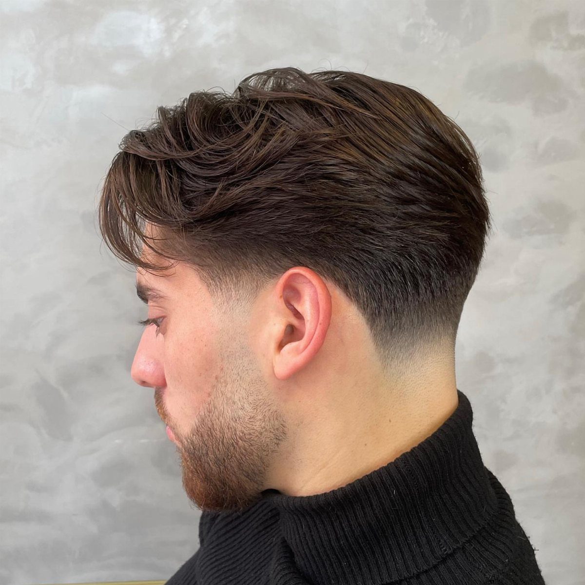 Man with a brown straight sleek quiff and a low taper fade haircut.