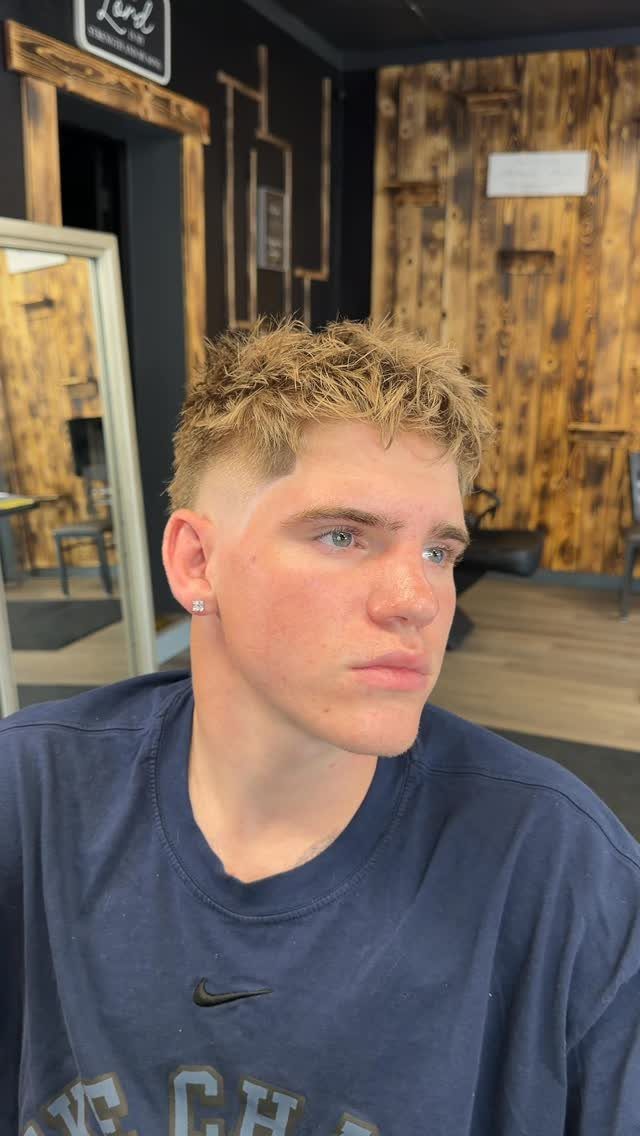 Young man with a textured fringe haircut and short faded sides in a barbershop.