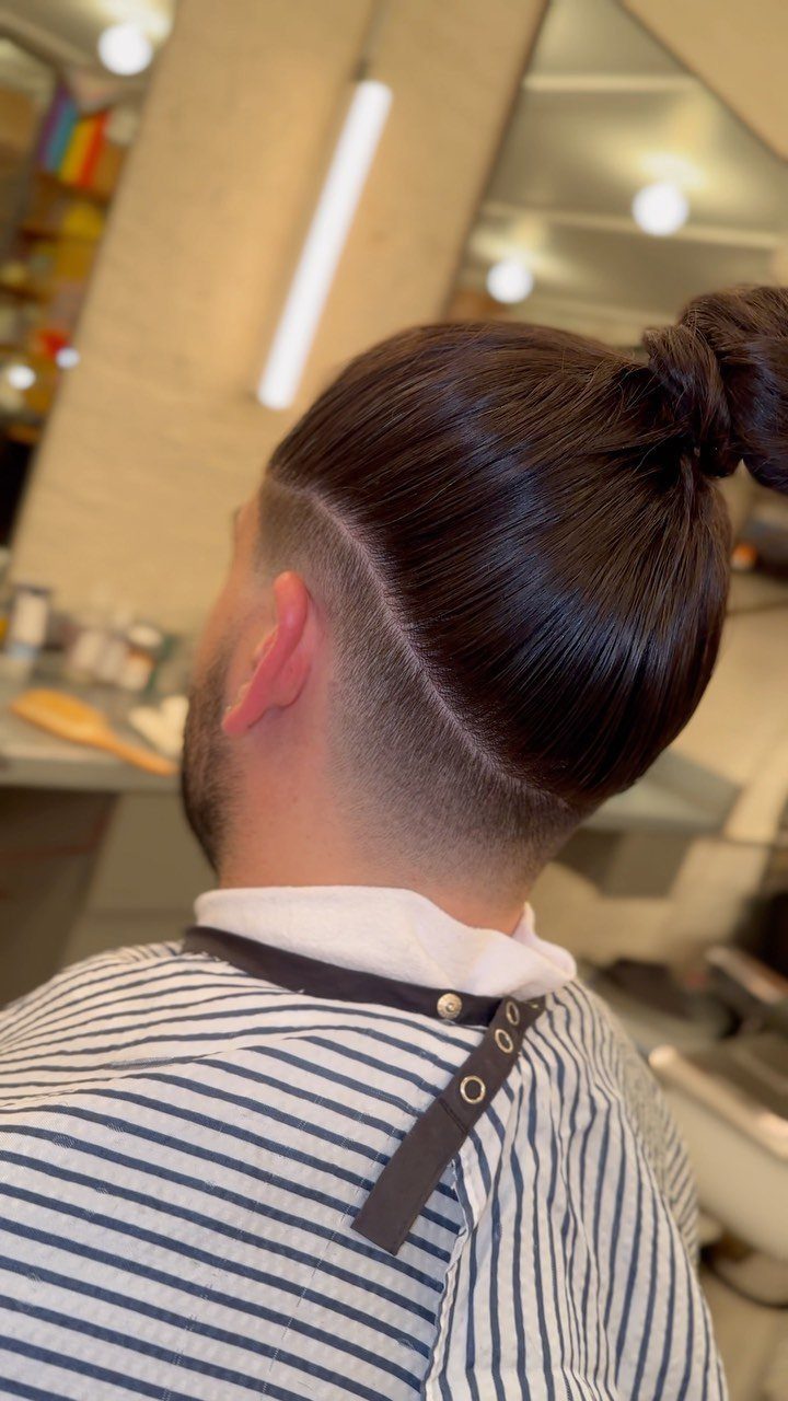 Man with a top knot and low taper fade undercut in a barbershop