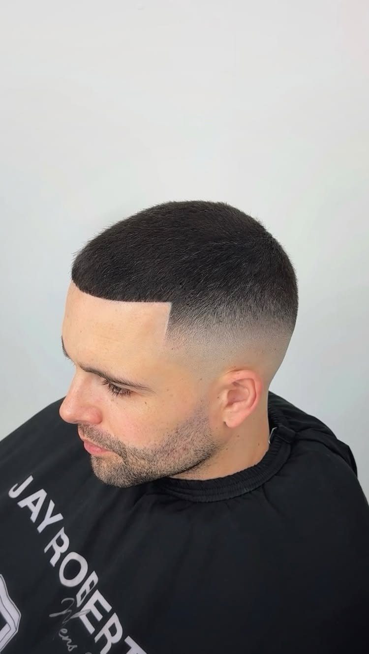 Man with a short buzz cut and low taper fade side profile