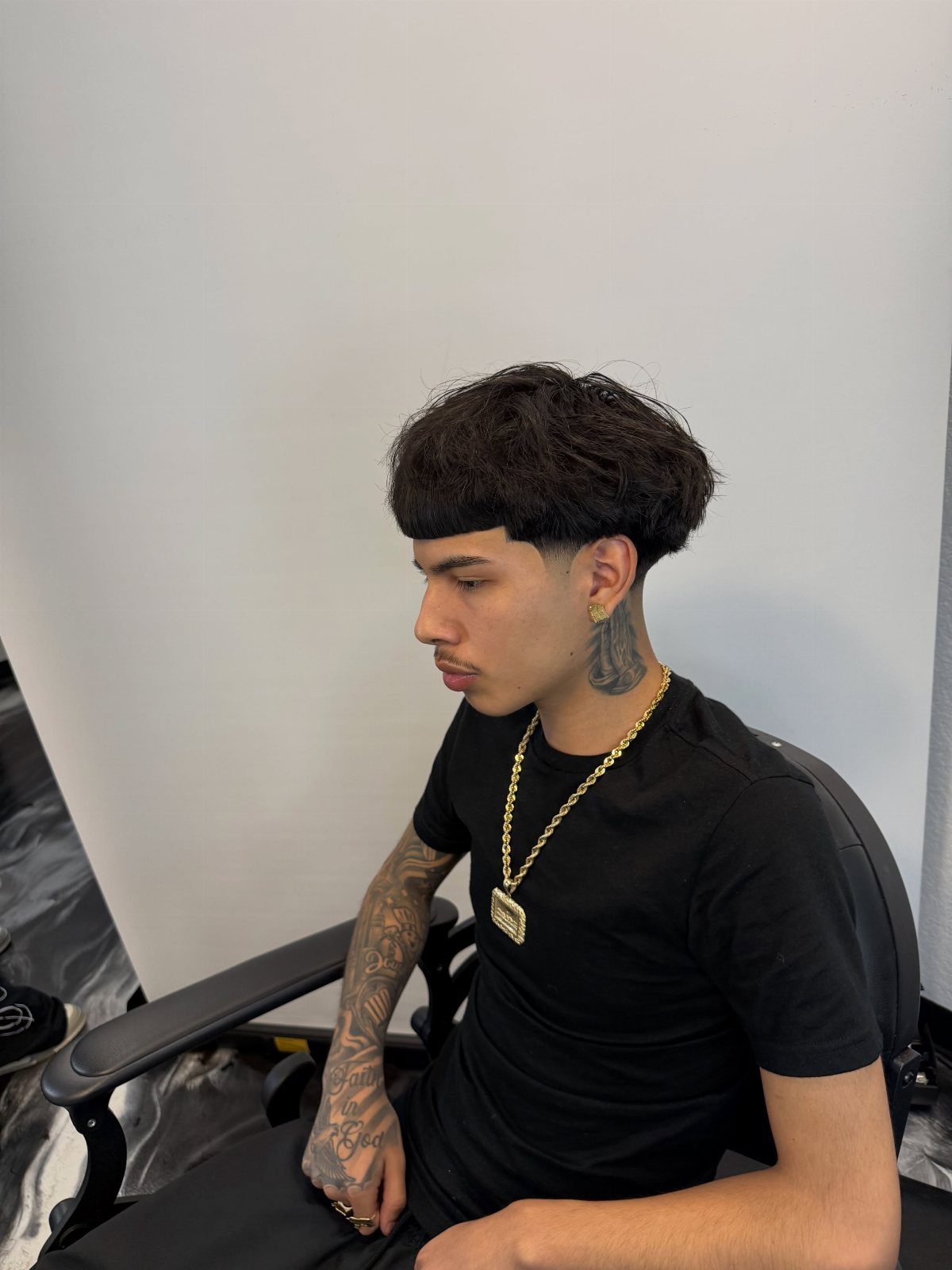 Man with a clean cropped cut and low taper fade wearing a gold chain.