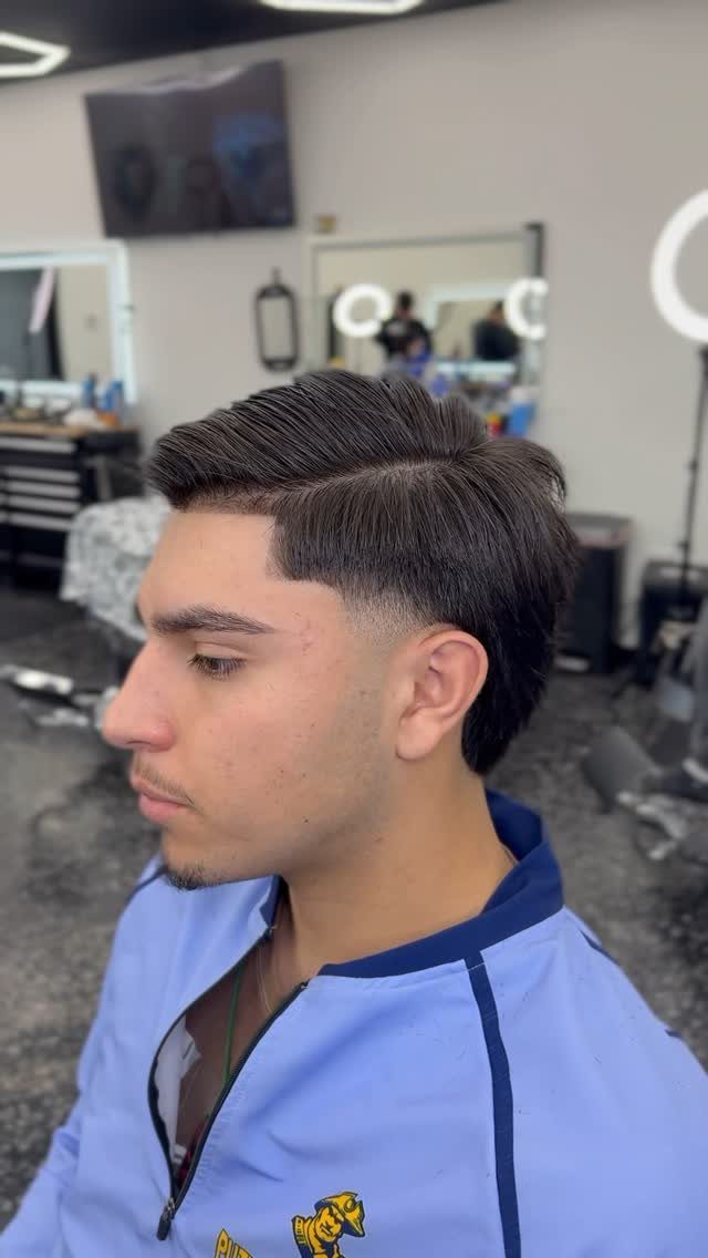 Man with a disconnected comb over and low taper fade in a barbershop