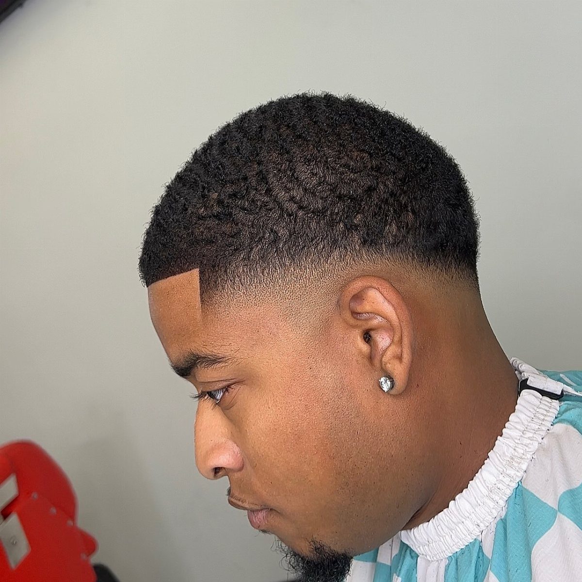 Man with a low drop taper fade haircut and short textured top.
