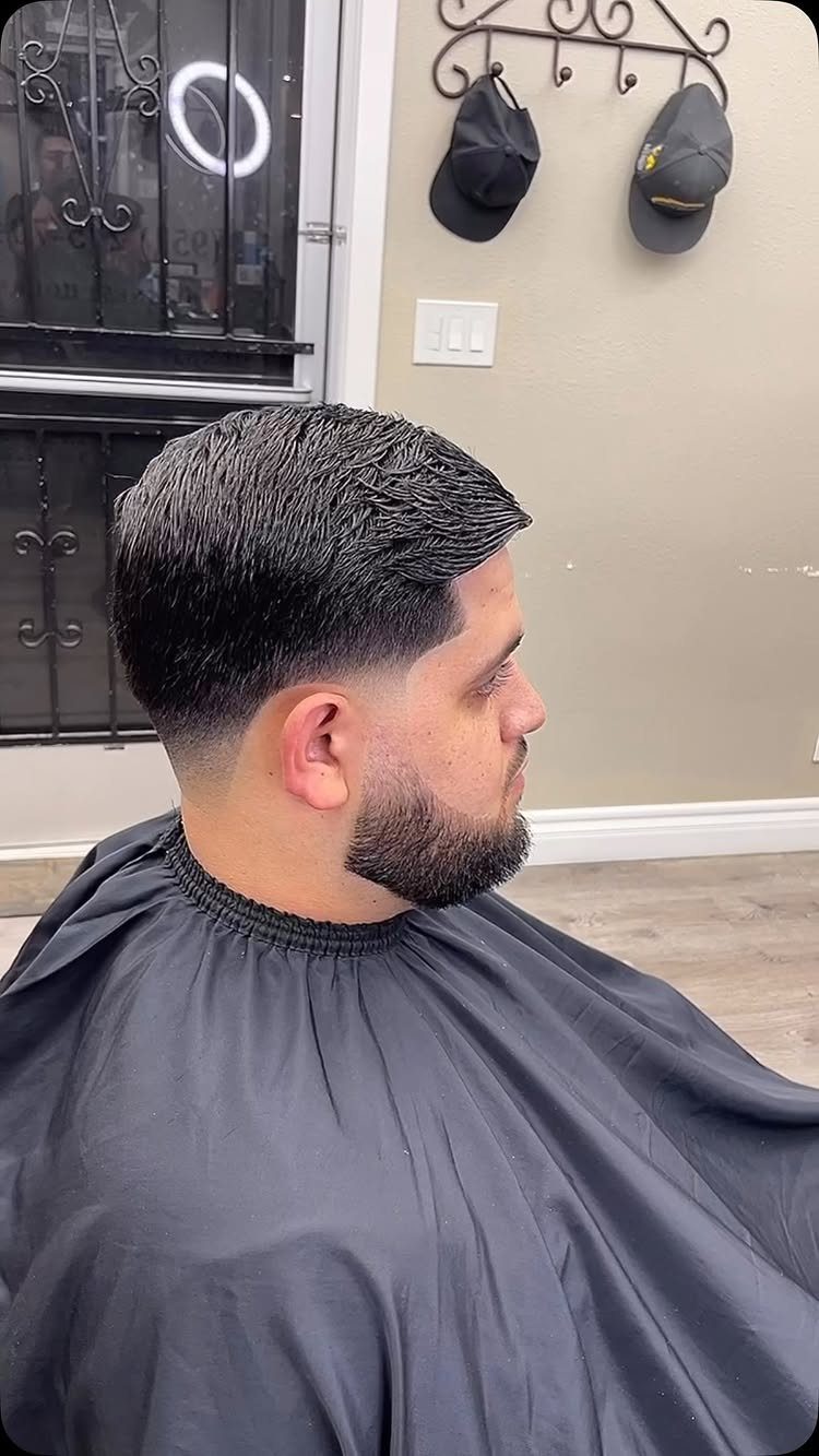 Man with a low taper fade haircut and a groomed dark beard.