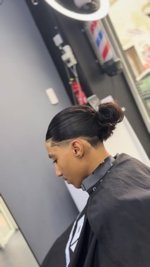 Man with a man bun and a clean low taper fade haircut.