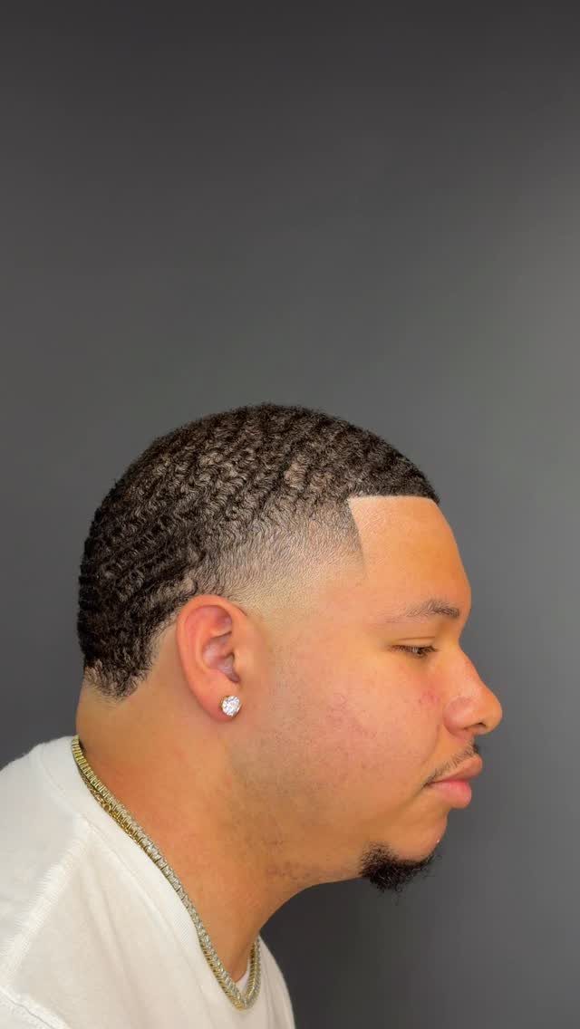 Man with a low taper fade and wave hair pattern in side profile.