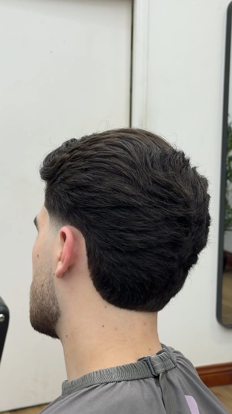 Man with dark brown side-swept short hair and a groomed beard in a salon.