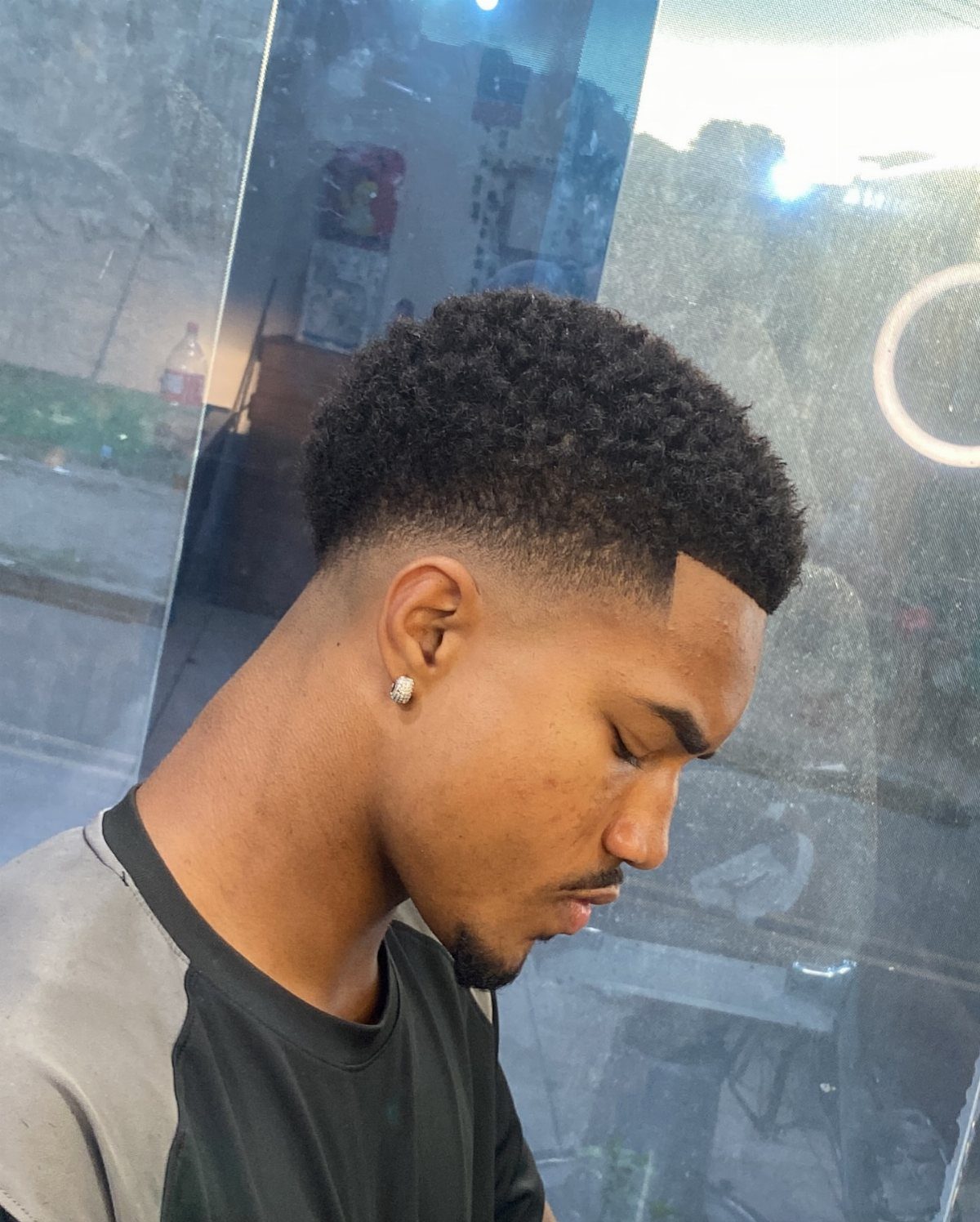 Man with a short tapered afro and a sharp, clean hairline profile view